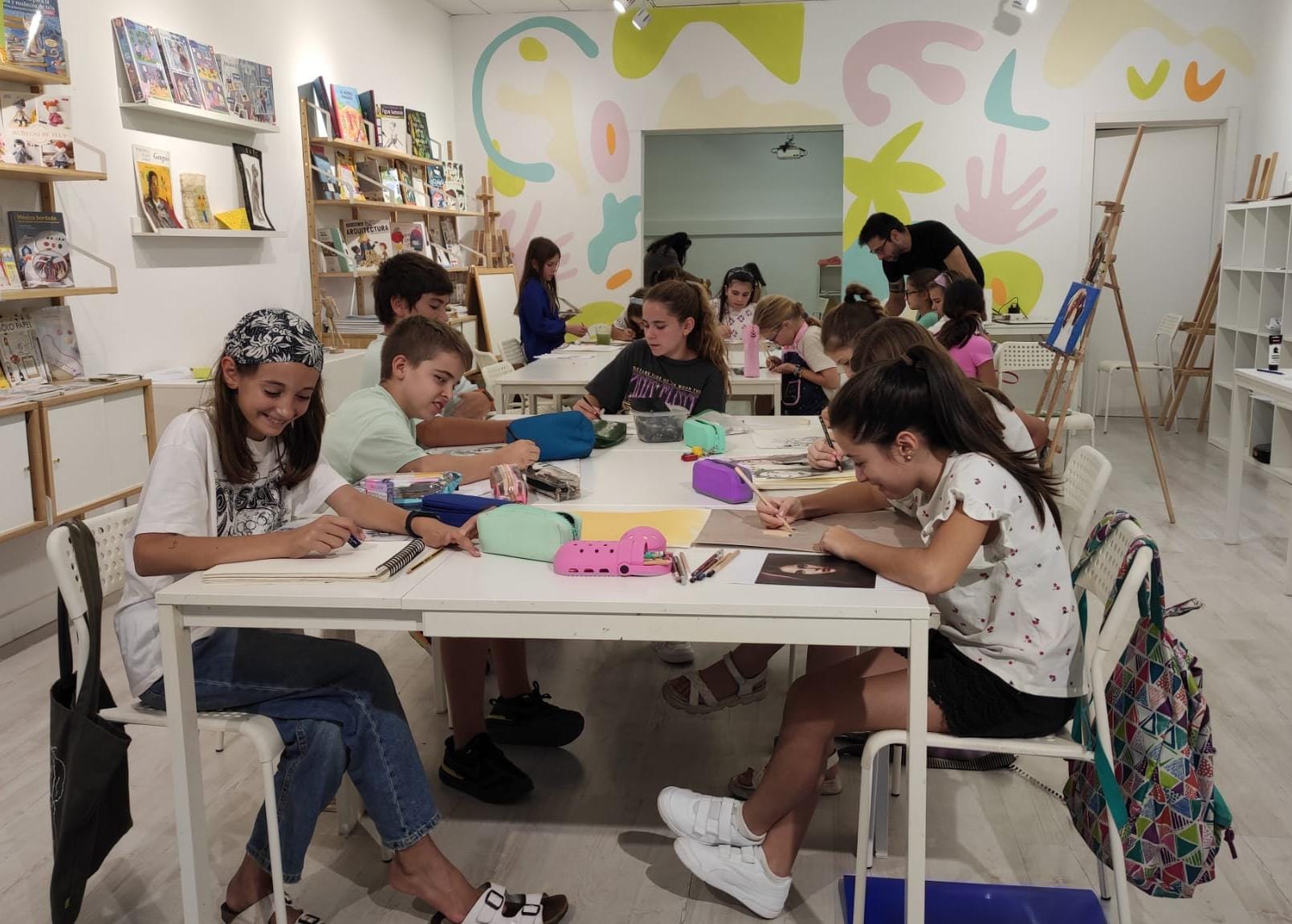 niños de mas de 12 años pintando sobre mesas blancas sentados en sillas