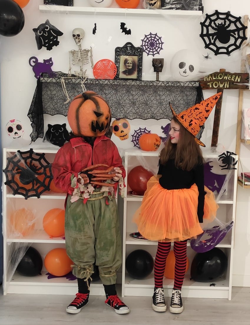 Dos niños disfrazados de calabaza y de bruja en el taller decorado de Halloween