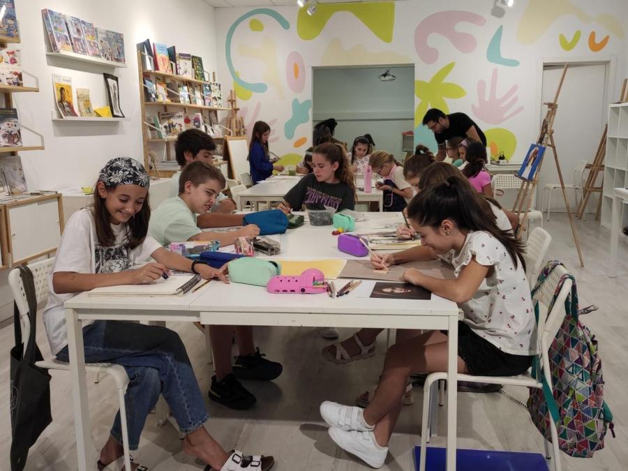 niños de mas de 12 años pintando sobre mesas blancas sentados en sillas